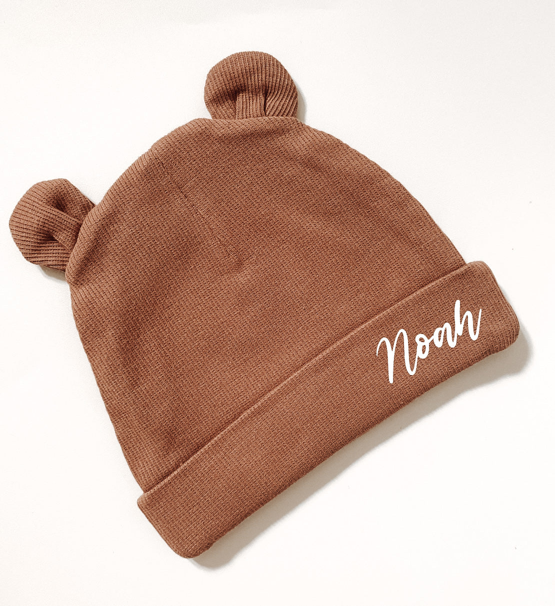 Brown baby hat with bear ears design. Name personalisation in white italic font.