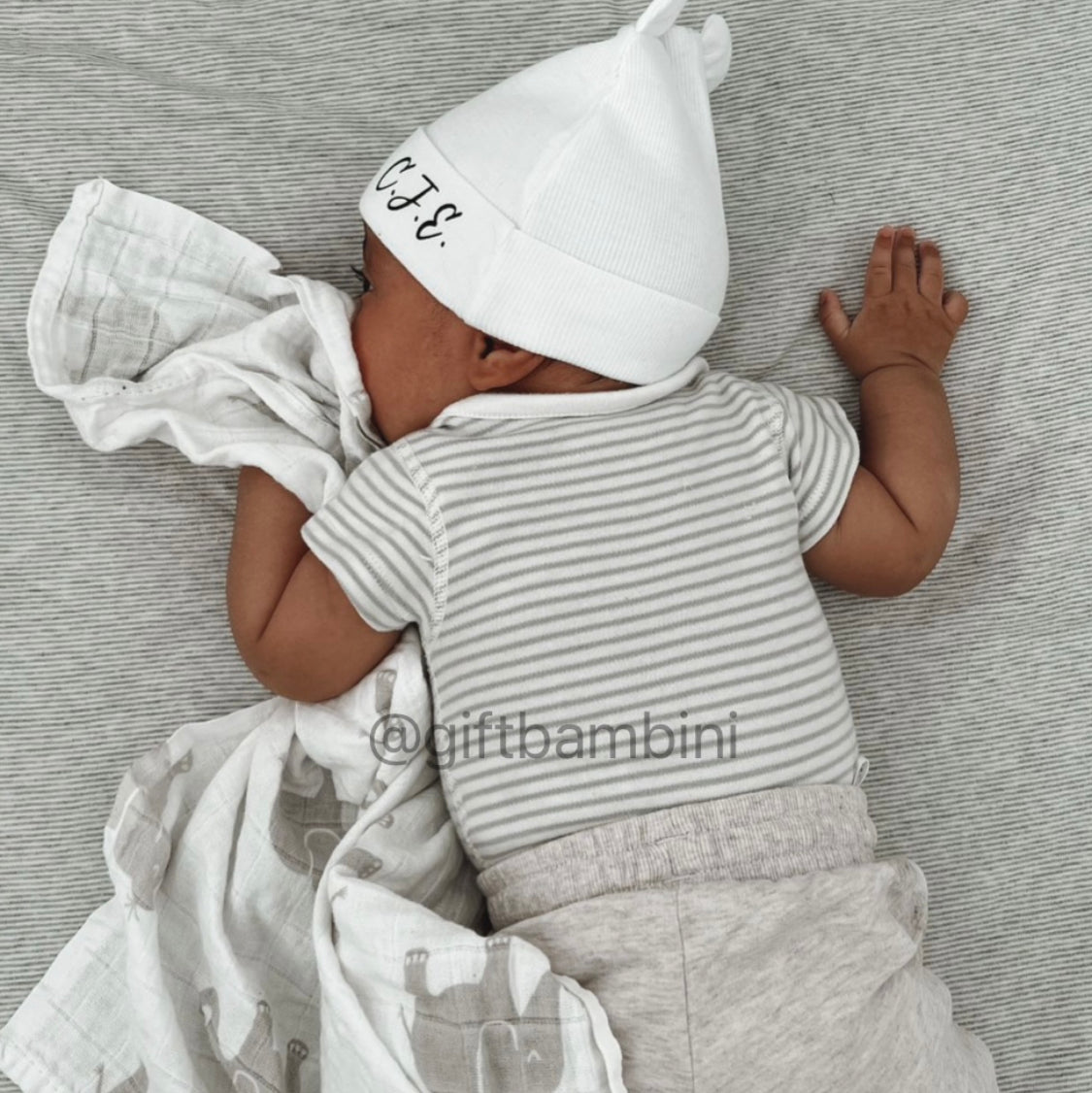 Image of baby wearing white baby hat with bear ears design and name personalisation C.J.E.